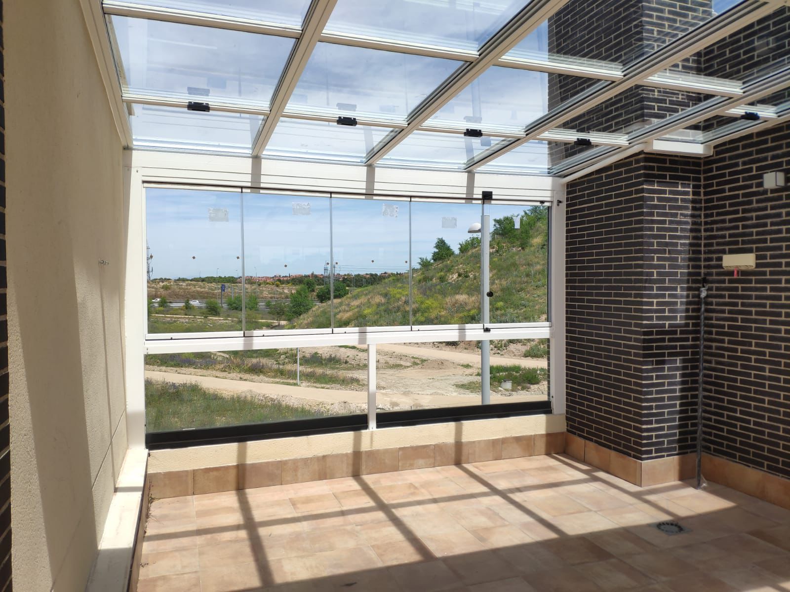 Cerramiento de patio con techo fijo de cristal y cortinas