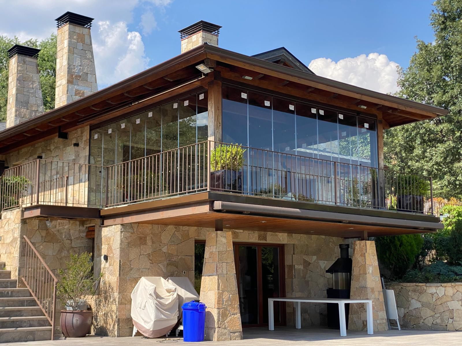Cerramiento de cristal en balcón de chalet de montaña con chimeneas