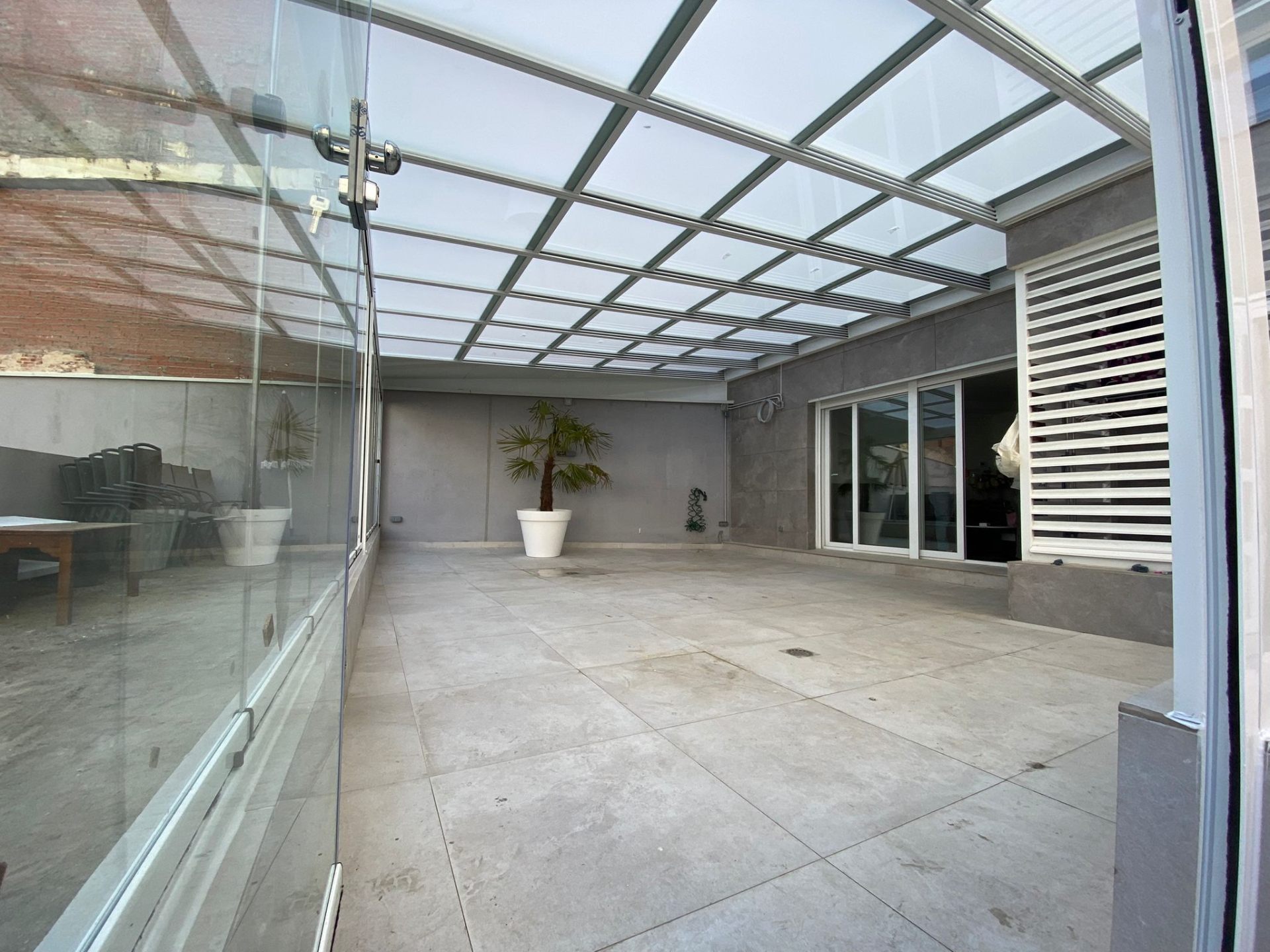 Patio interior cerrado con techo móvil de cristal
