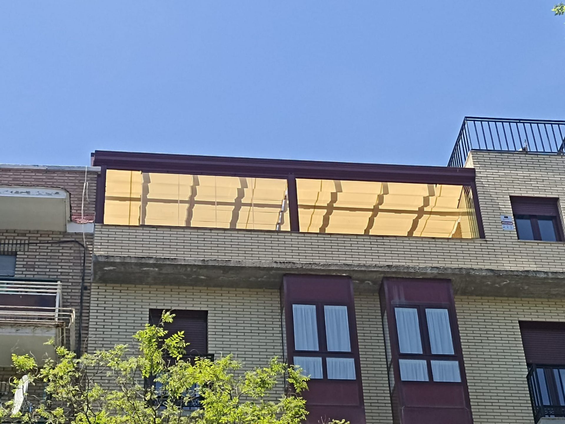 Cerramiento de ático con toldo y techo de cristal en edificio