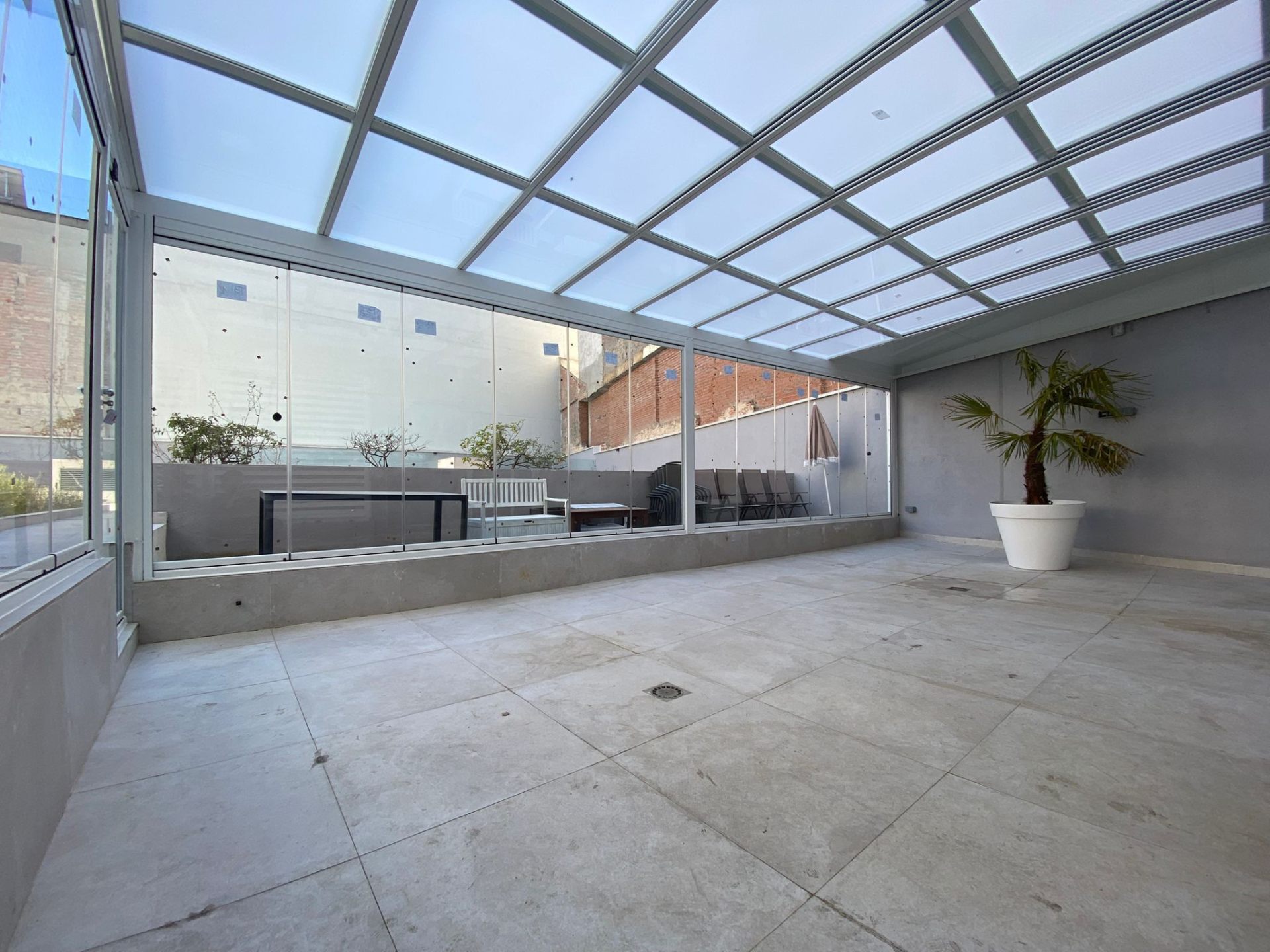Patio cerrado con cortinas de cristal y techo móvil panorámico