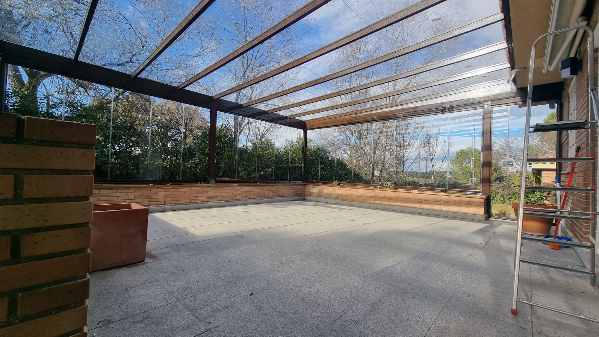 Techo fijo de cristal con vigas de madera sobre terraza