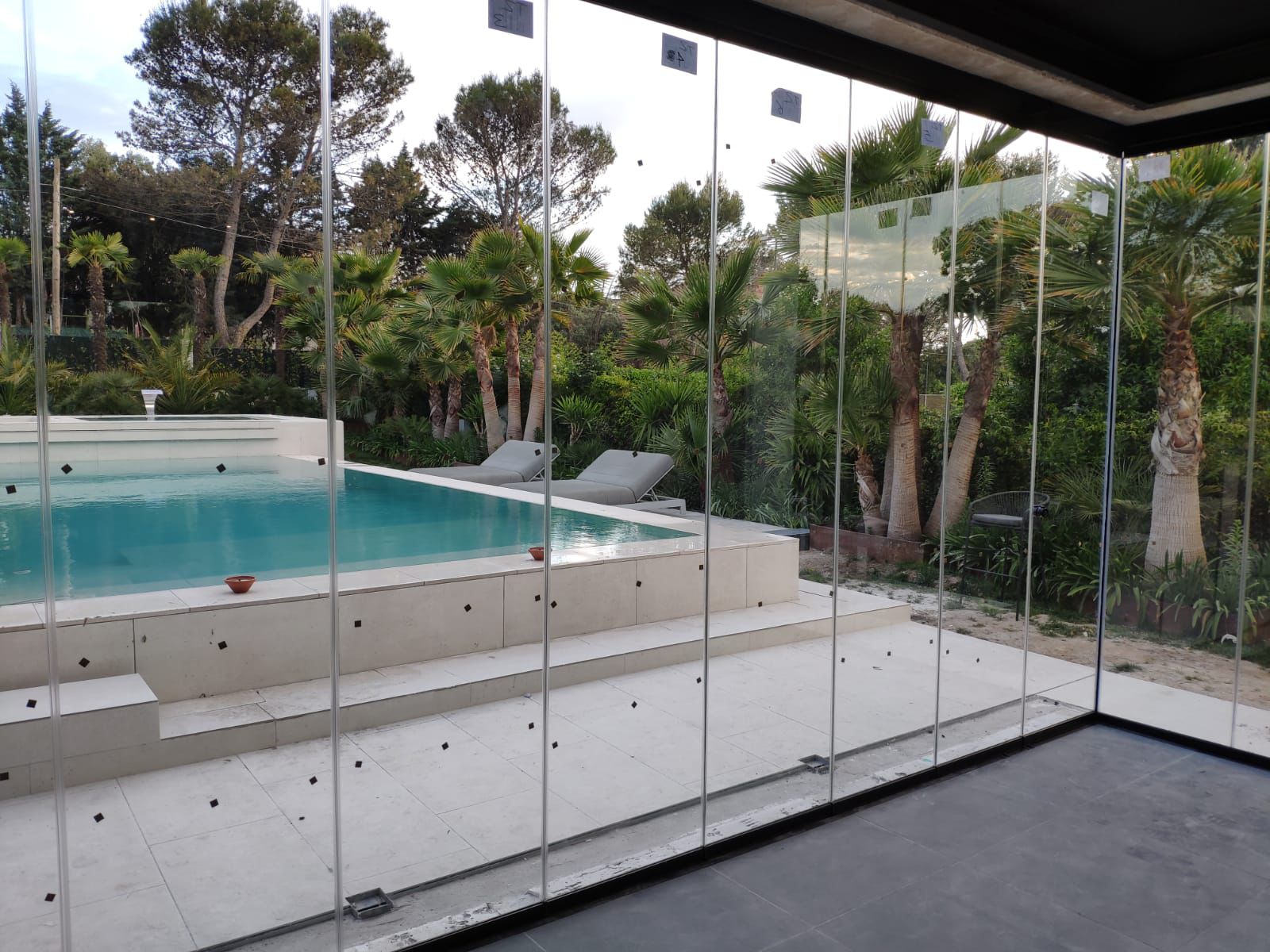 Cortina de cristal en porche con vistas a piscina y palmeras