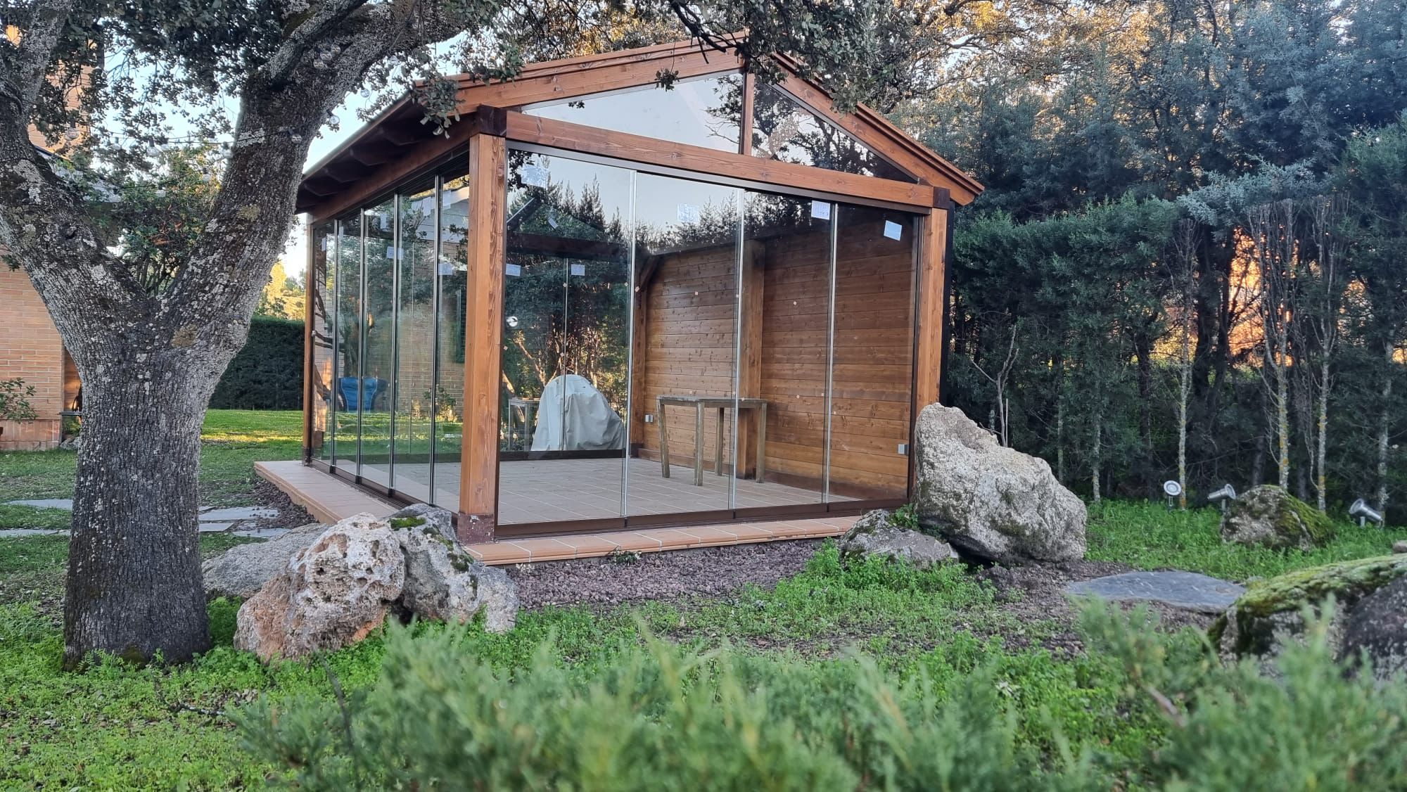 Cenador de cristal con estructura de madera en jardín