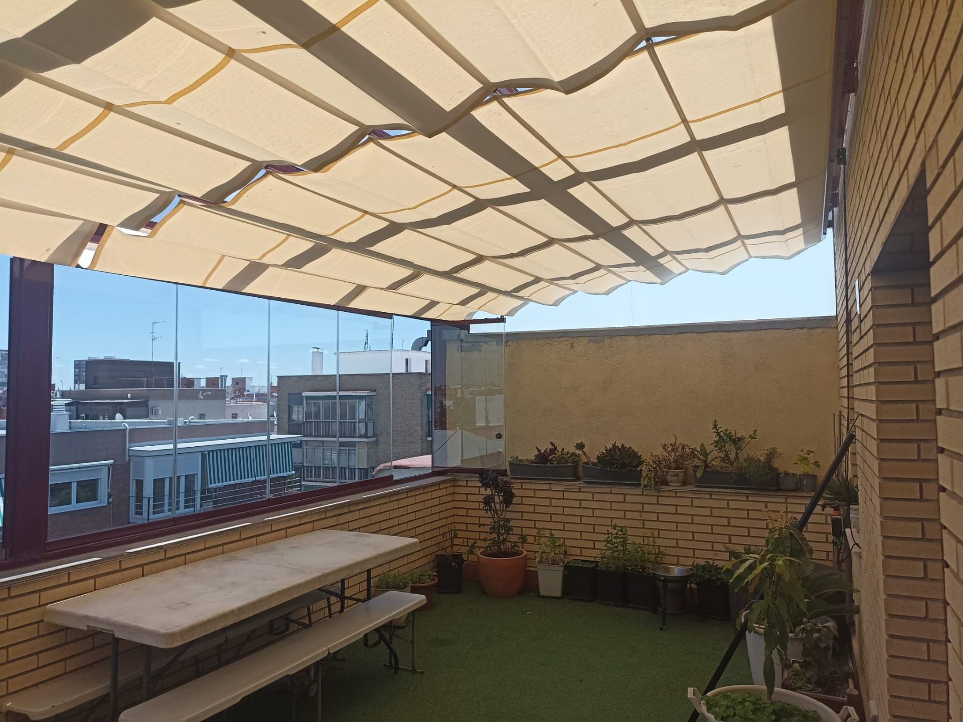 Ático con cortina de cristal y toldo de lamas en Madrid