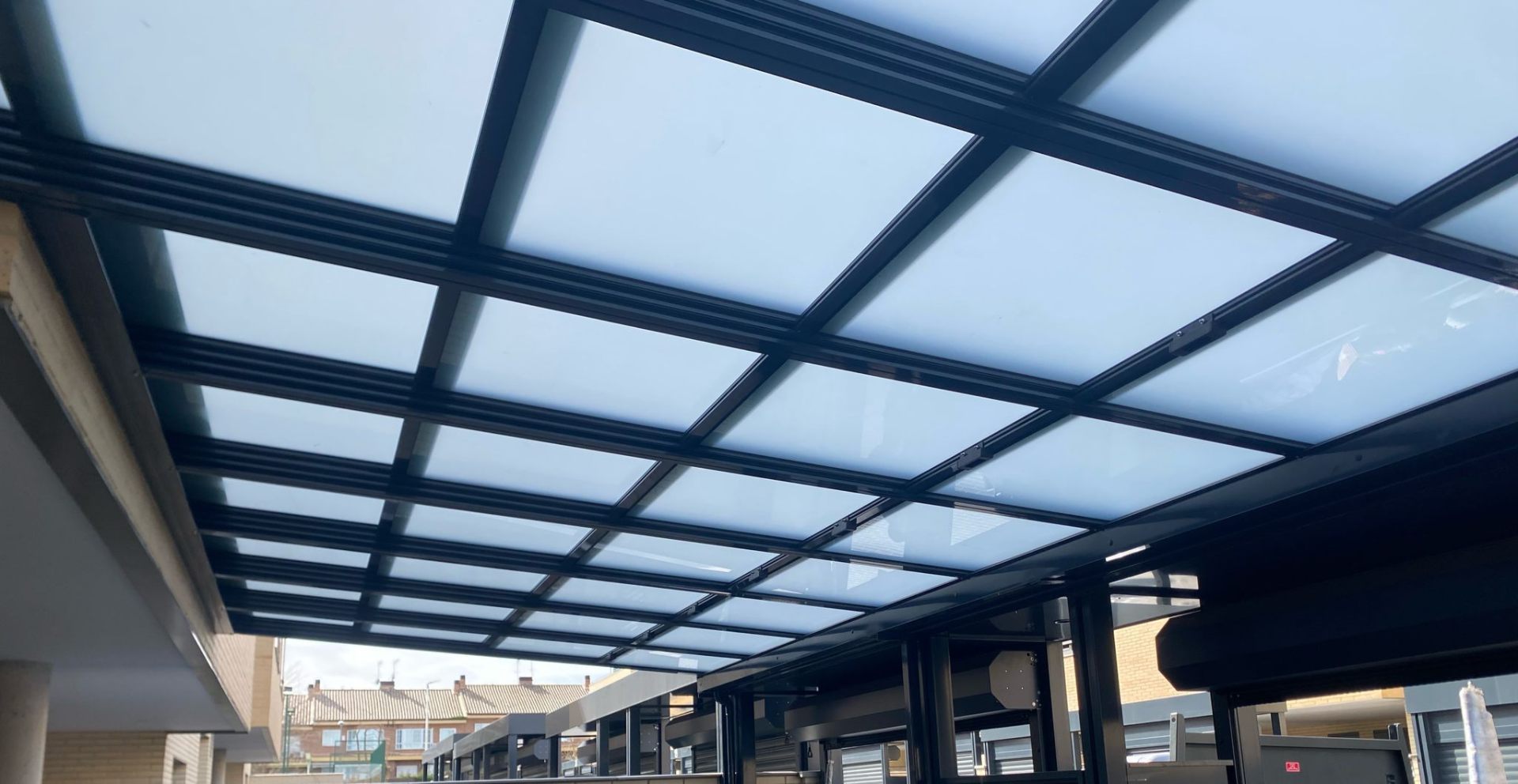 Techo fijo de cristal con perfilería negra sobre terraza
