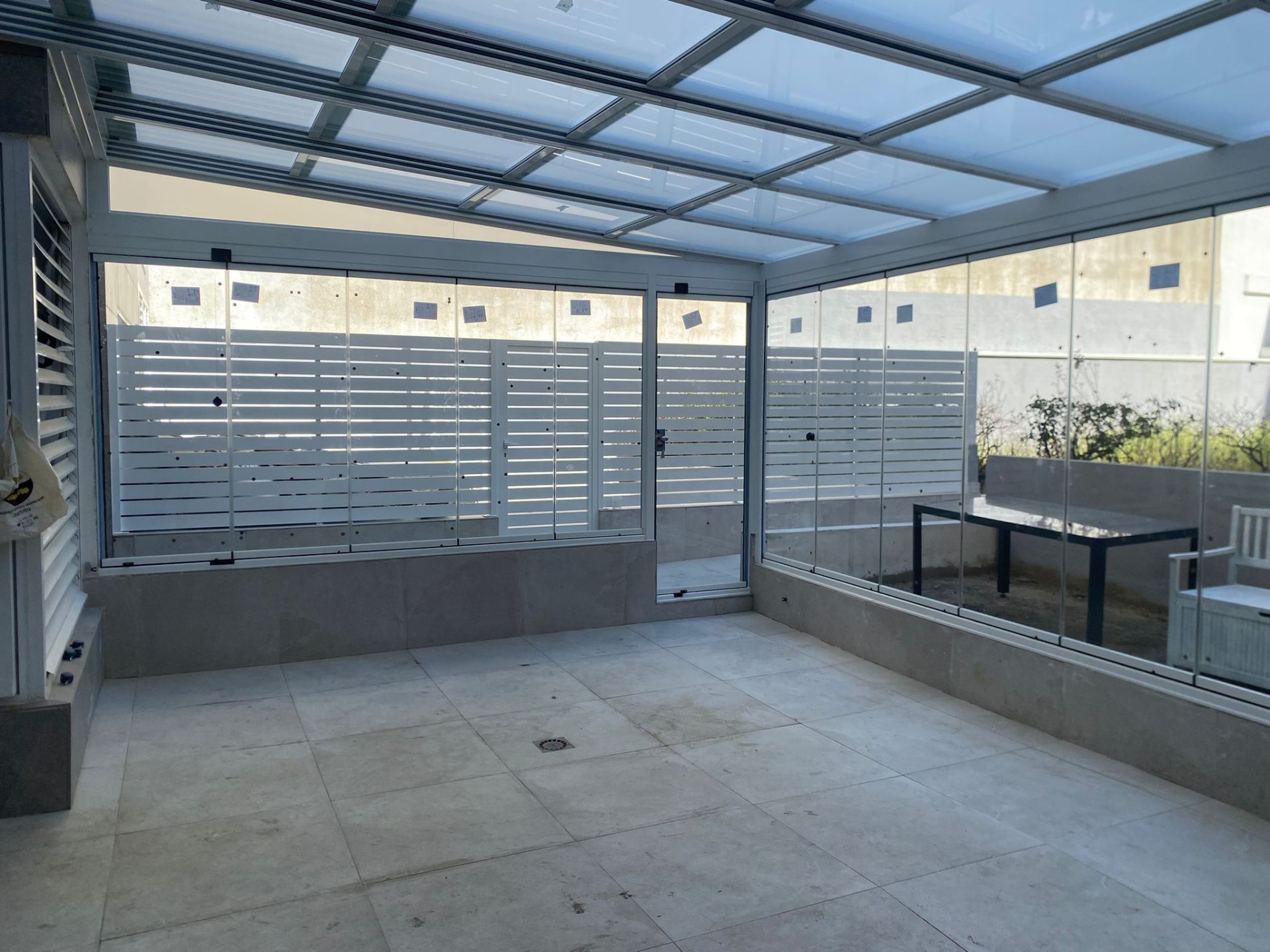 Cerramiento de patio con cortinas de cristal y techo móvil